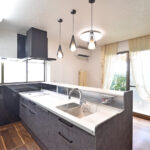 新設された対面キッチンのカウンター収納と、デザインを統一した背面の大型カップボード。見せる収納にこだわった事例。