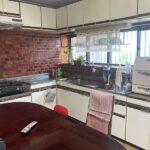 大竹市M様邸のリフォーム前施工事例画像。赤いレンガ壁が特徴的なL型キッチンで、吊戸棚によって手元が暗い状態。