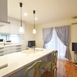 リフォーム後のキッチン。背面に設置された大容量の白いカップボードと、おしゃれなペンダントライト。