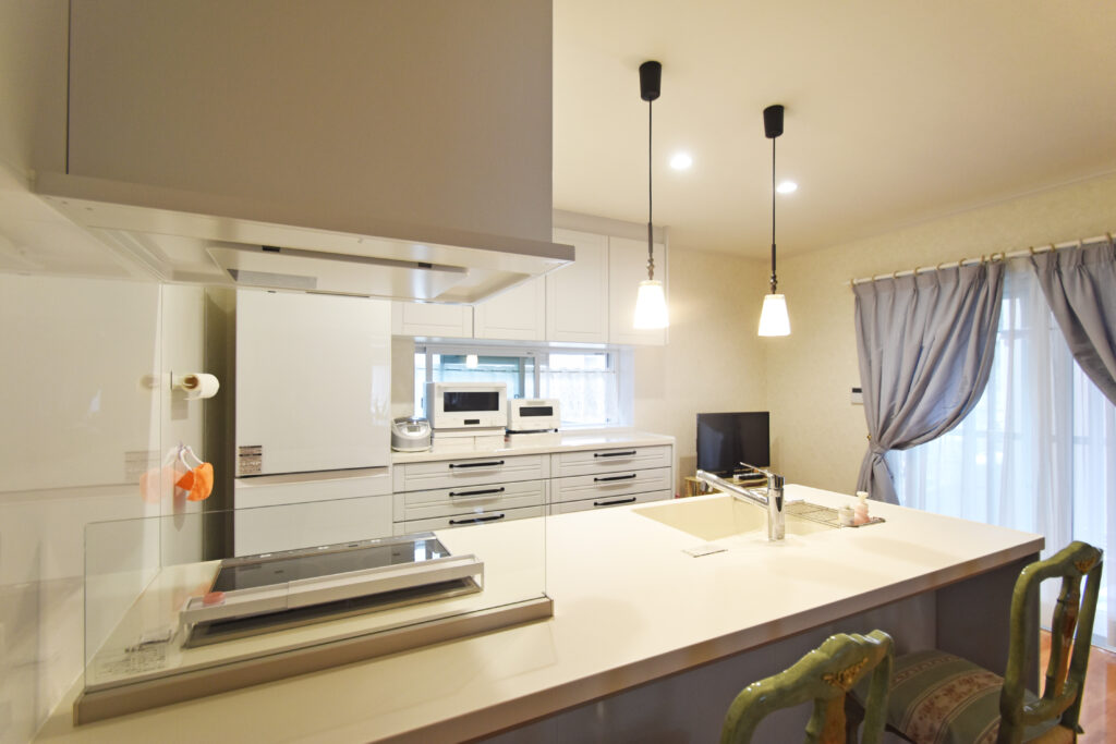 リフォーム後のキッチン。背面に設置された大容量の白いカップボードと、おしゃれなペンダントライト。