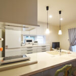 リフォーム後のキッチン。背面に設置された大容量の白いカップボードと、おしゃれなペンダントライト。