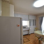 大竹市T様邸リフォーム前。壁に向かって作業するタイプのキッチン。花柄の壁紙と使い込まれた収納が特徴。