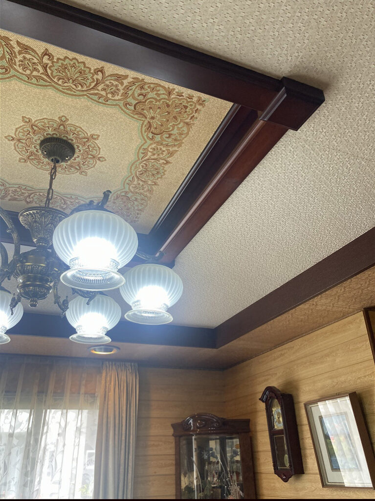 大竹市M様邸リフォーム前の折り上げ天井。木枠にベージュの伝統柄クロスとシャンデリアが設置された様子。