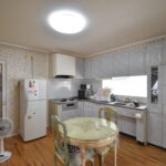 大竹市T様邸リフォーム前。壁に向かって作業するタイプのキッチン。花柄の壁紙と使い込まれた収納が特徴。