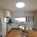 大竹市T様邸リフォーム前。壁に向かって作業するタイプのキッチン。花柄の壁紙と使い込まれた収納が特徴。